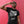 Load image into Gallery viewer, A man standing against a bright red wall wearing the Hombre Lobo shirt that depicts an abstract werewolf face.