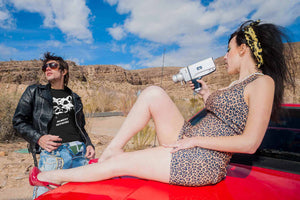 A woman filming a man wearing the Almost Official Hombre Lobo shirt.