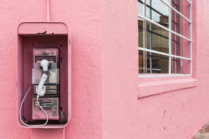 A bright pink building with a broken pay phone.