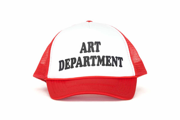 The front of a red and white trucker hat with the text Art Department printed in black. 