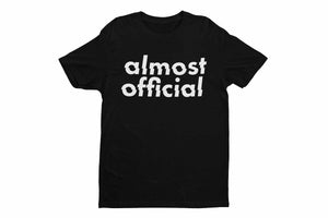 A black Almost Official glitch logo shirt on a white background.