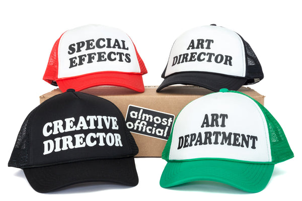 A group photo of a black, black and white, red and white, and green and white trucker hats with a variety of titles printed on the front panel. 