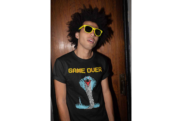 A cool young man wearing a black Cobra Boss shirt that depicts a colorful 8 bit cobra and the words Game Over.